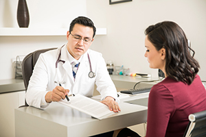 A male doctor is pointing a clipboard and explaining information to a female patient
